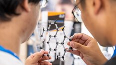 Zwei Männer halten ein hexagonales Gitter aus Plastik-Steckverbindungen.